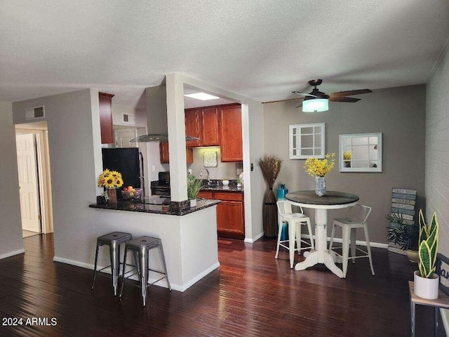 kitchen featuring kitchen peninsula, a textured ceiling, dark hardwood / wood-style floors, and black fridge