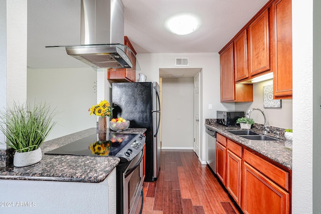 kitchen featuring dark stone counters, sink, hardwood / wood-style flooring, appliances with stainless steel finishes, and island exhaust hood