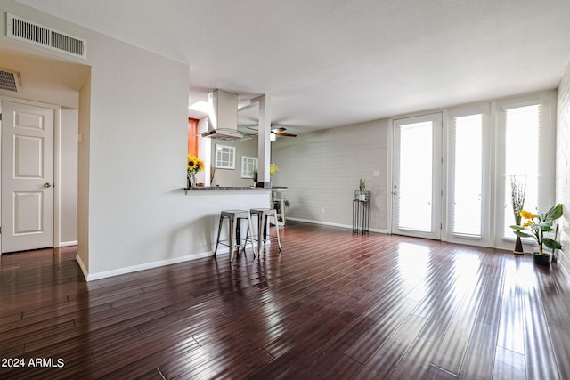 living room with dark hardwood / wood-style flooring, ceiling fan, and a healthy amount of sunlight