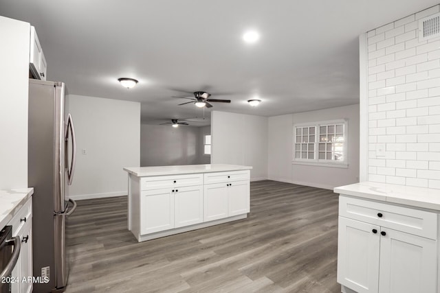 kitchen with hardwood / wood-style floors, stainless steel fridge, light stone countertops, and white cabinetry