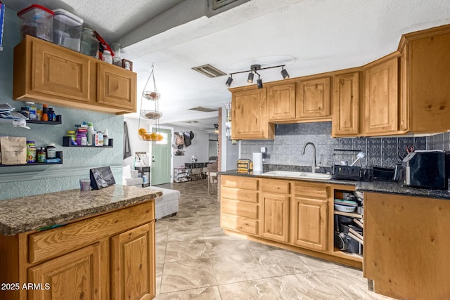 kitchen featuring pendant lighting, sink, dark stone countertops, a textured ceiling, and decorative backsplash