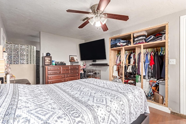 bedroom featuring hardwood / wood-style floors, a textured ceiling, a closet, and ceiling fan