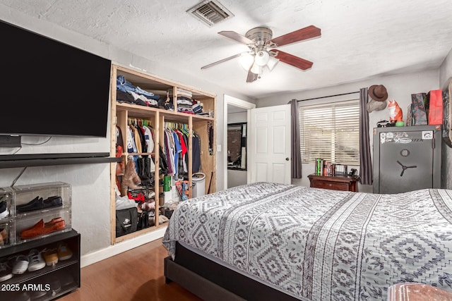 bedroom with dark wood-type flooring, a textured ceiling, ceiling fan, and a closet