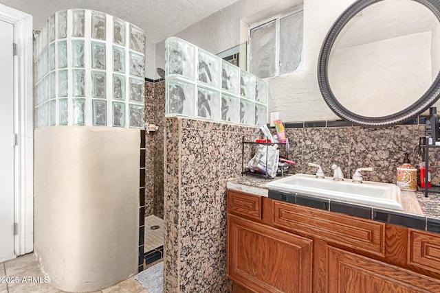 bathroom featuring tasteful backsplash, vanity, and tiled shower