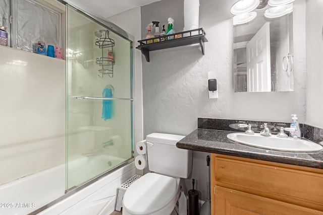 full bathroom with enclosed tub / shower combo, vanity, and toilet