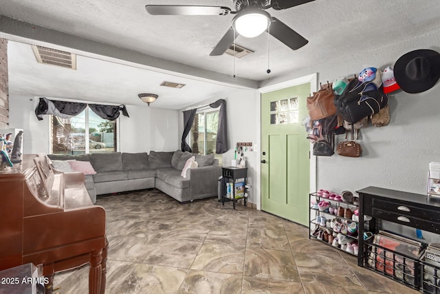 living room featuring ceiling fan, a textured ceiling, and a healthy amount of sunlight