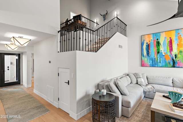 living room featuring a towering ceiling and light hardwood / wood-style flooring