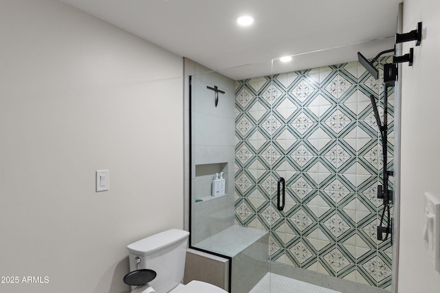 bathroom with a tile shower and toilet