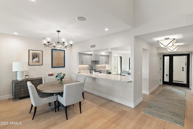 dining space with an inviting chandelier, sink, and light hardwood / wood-style floors