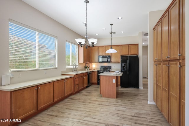 kitchen with black appliances, hanging light fixtures, sink, light hardwood / wood-style floors, and a center island