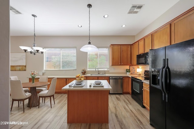 kitchen featuring hanging light fixtures, light hardwood / wood-style flooring, black appliances, and sink