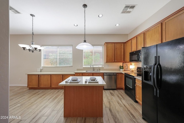 kitchen featuring light hardwood / wood-style floors, sink, black appliances, decorative light fixtures, and a center island