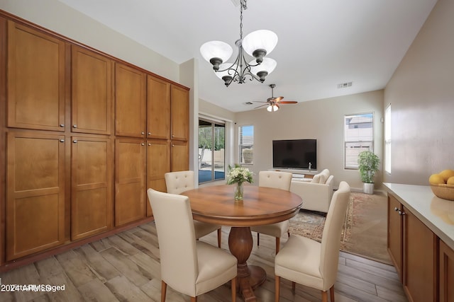 dining room with ceiling fan with notable chandelier and light hardwood / wood-style floors