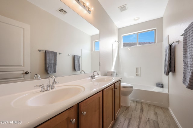 full bathroom featuring hardwood / wood-style floors, vanity, toilet, and shower / washtub combination