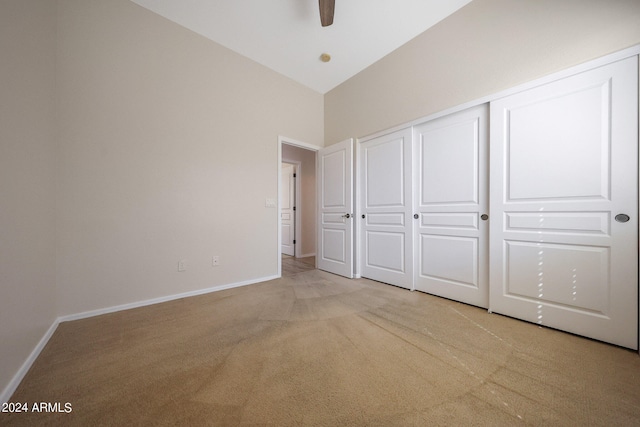 unfurnished bedroom with high vaulted ceiling, light carpet, ceiling fan, and a closet