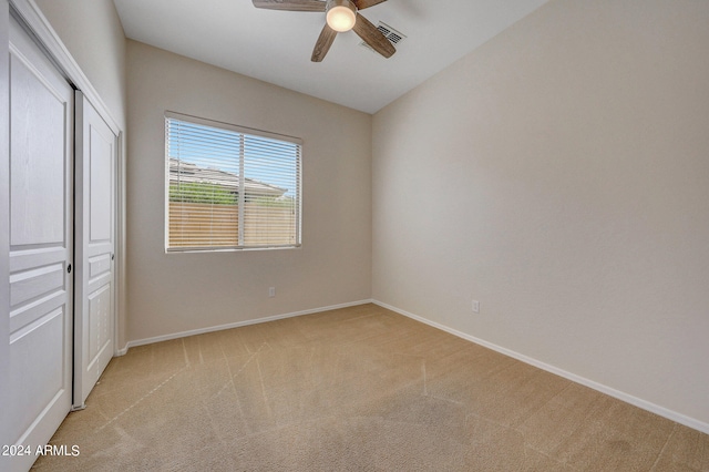 unfurnished bedroom with ceiling fan, a closet, and light colored carpet