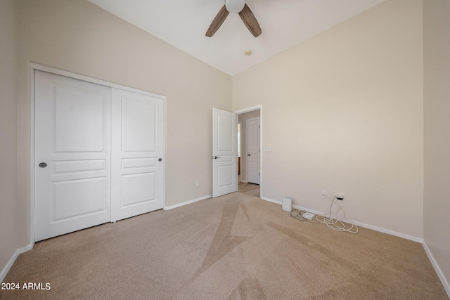 unfurnished bedroom featuring a closet, vaulted ceiling, light carpet, and ceiling fan