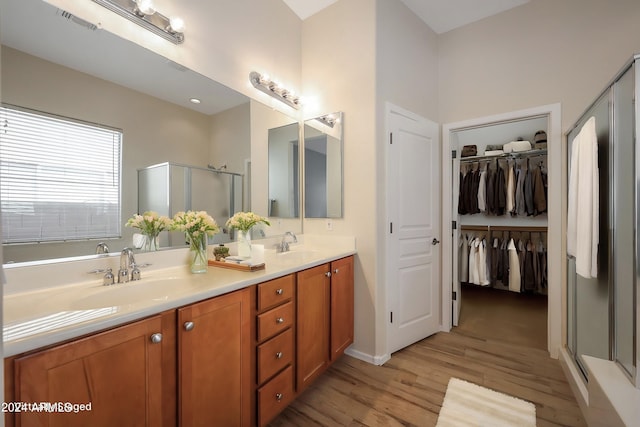 bathroom with wood-type flooring, vanity, and an enclosed shower