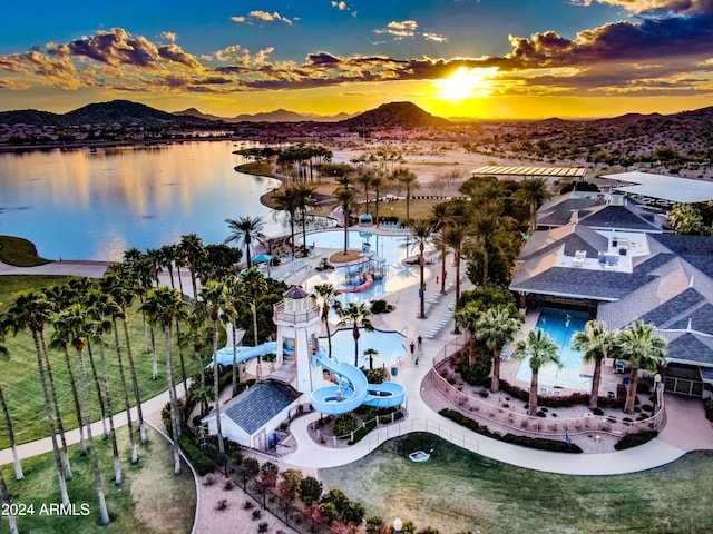 aerial view at dusk featuring a water and mountain view