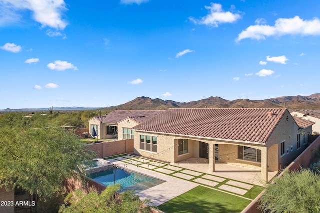 rear view of property with a mountain view, a patio, and a pool with hot tub