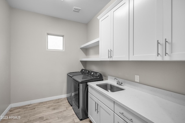 washroom with washer and clothes dryer, sink, cabinets, and light hardwood / wood-style flooring