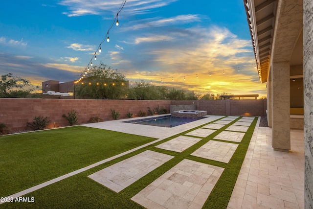 yard at dusk featuring a swimming pool with hot tub and a patio