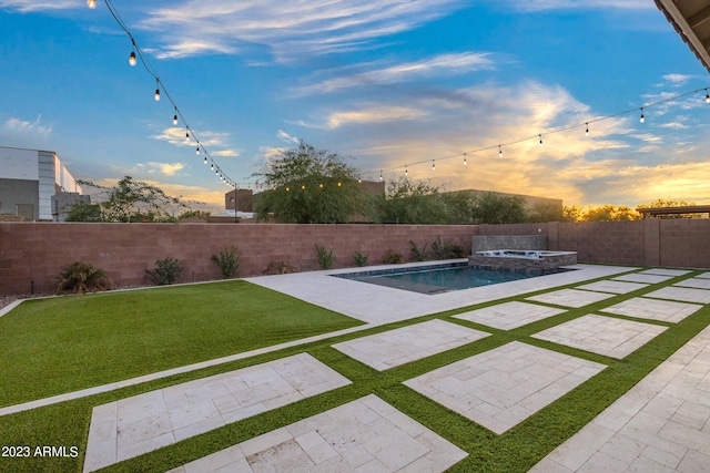 pool at dusk with an in ground hot tub, a patio area, and a lawn