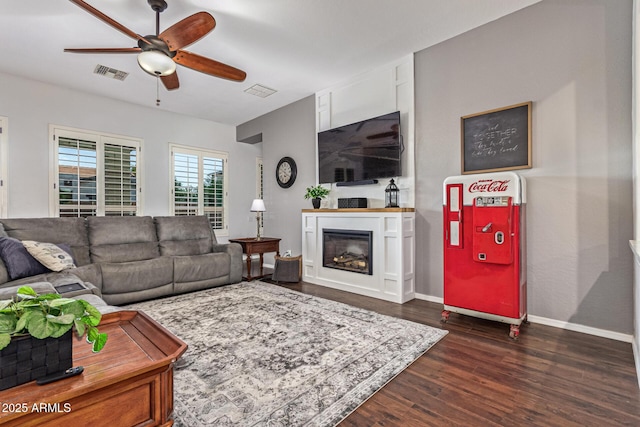2045 E San Carlos Pl, Chandler, AZ 85249 - living room featuring a ceiling fan, a glass covered fireplace, dark wood-style flooring, and baseboards