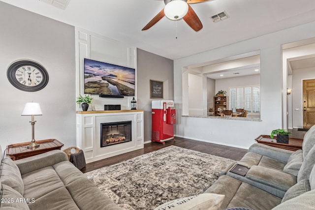 2045 E San Carlos Pl, Chandler, AZ 85249 - living area featuring ceiling fan, dark wood finished floors, a glass covered fireplace, and baseboards