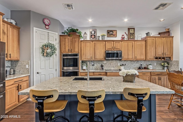 2045 E San Carlos Pl, Chandler, AZ 85249 - kitchen featuring appliances with stainless steel finishes, a sink, tasteful backsplash, dark wood-style floors, and a center island with sink