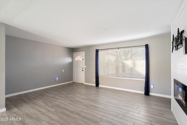 unfurnished living room with a fireplace and light wood-type flooring