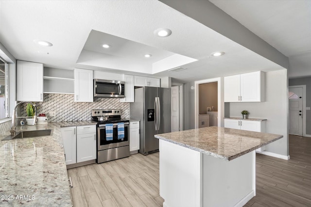 kitchen featuring sink, appliances with stainless steel finishes, white cabinetry, light stone counters, and washer and dryer