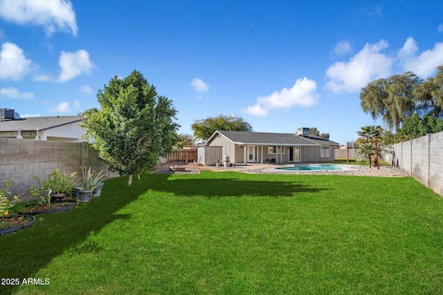 rear view of property featuring a fenced in pool, a patio area, and a lawn