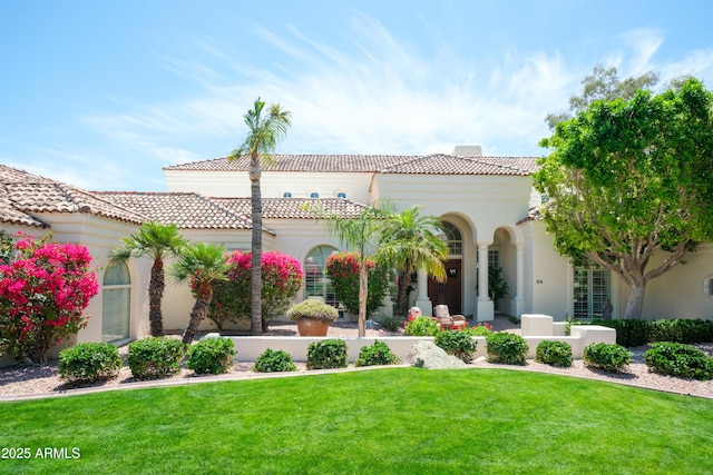 mediterranean / spanish home with stucco siding, a tiled roof, and a front yard
