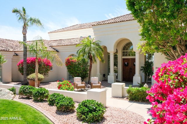 property entrance with a tiled roof, fence, and stucco siding