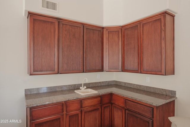 kitchen with visible vents, brown cabinetry, and a sink