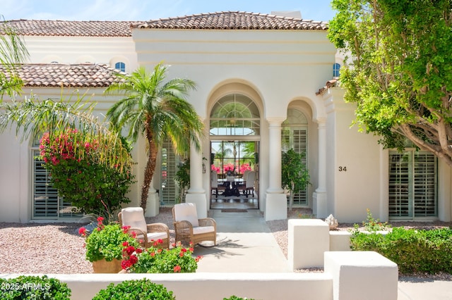 entrance to property featuring stucco siding, a porch, and a tile roof