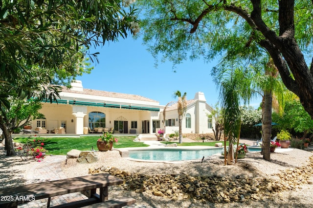 rear view of property featuring stucco siding, a chimney, a patio area, and an outdoor pool