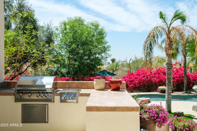 view of patio featuring area for grilling, exterior kitchen, and an outdoor pool