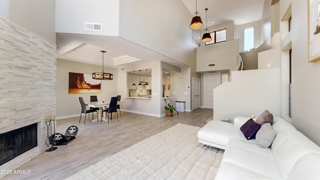 25555 N Windy Walk Dr Unit 64, Scottsdale, AZ 85255 - living area with light wood-style flooring, a towering ceiling, a stone fireplace, and baseboards