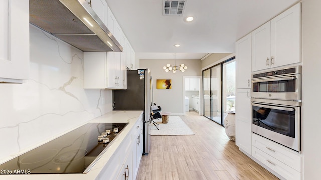 25555 N Windy Walk Dr Unit 64, Scottsdale, AZ 85255 - kitchen with under cabinet range hood, appliances with stainless steel finishes, white cabinets, a chandelier, and light stone countertops