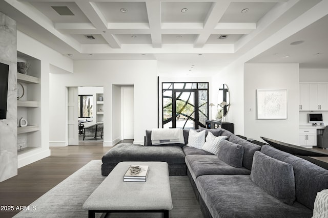 living room featuring beam ceiling, hardwood / wood-style floors, a towering ceiling, and built in features