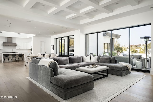 living room featuring coffered ceiling, a towering ceiling, wood-type flooring, and beamed ceiling