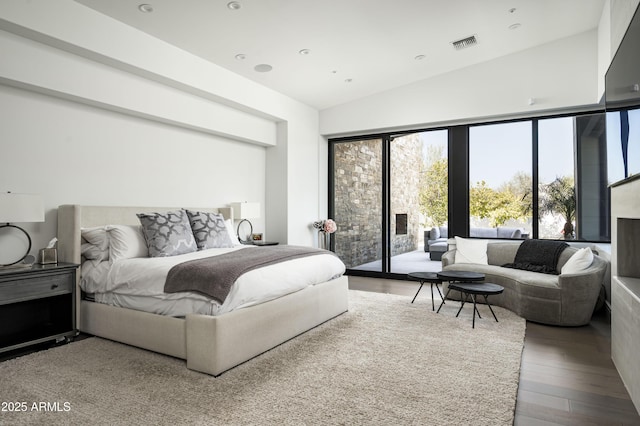 bedroom with wood-type flooring, vaulted ceiling, and access to outside