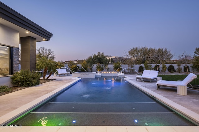 pool at dusk featuring a patio and pool water feature