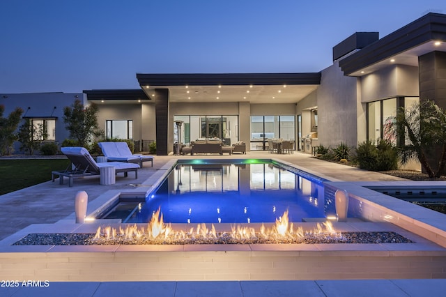 pool at dusk with a patio area and a fire pit