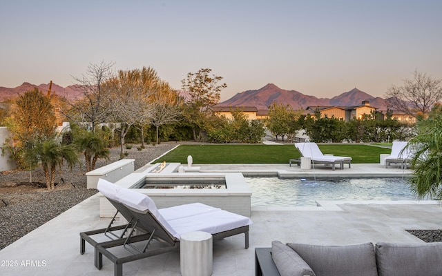 patio terrace at dusk featuring pool water feature, a mountain view, and a fire pit