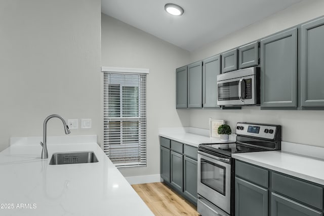 kitchen featuring gray cabinets, sink, vaulted ceiling, and appliances with stainless steel finishes