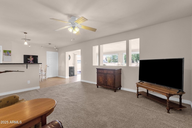 living area featuring rail lighting, light colored carpet, ceiling fan, and baseboards