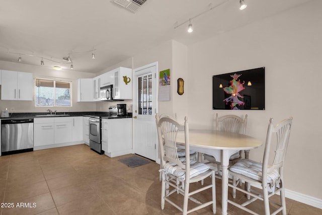 kitchen featuring dark countertops, visible vents, appliances with stainless steel finishes, white cabinets, and a sink